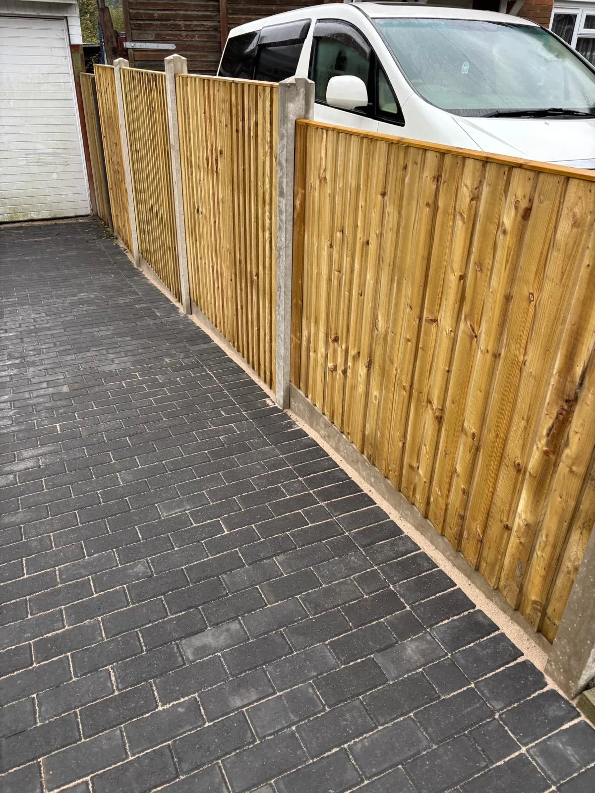 New close-board timber fence panels on concrete posts beside a block paved driveway