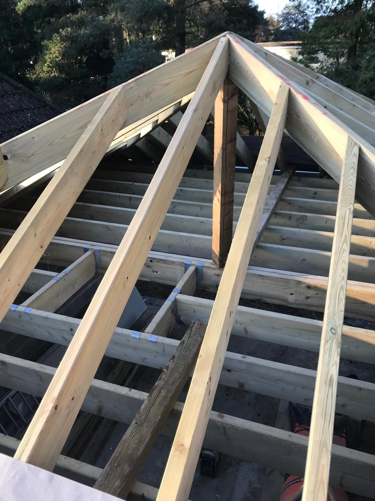 New timber roof rafters and ridge in place on a pitched roof, before tiling